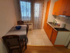 eine kleine Küche mit einem Tisch und einem Waschbecken in der Unterkunft Stan na dan Prnjavor, Gajba u centru in Prnjavor