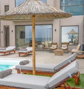 a patio with an umbrella next to a swimming pool at Ligaria Mare in Agia Pelagia