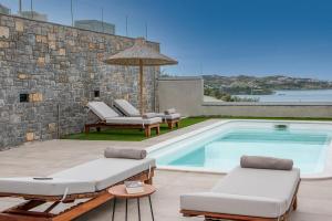 a swimming pool with two lounge chairs and an umbrella at Ligaria Mare in Agia Pelagia