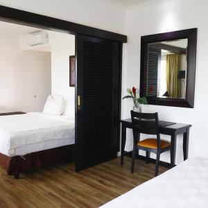 a bedroom with a bed and a desk and a mirror at Jakarta Airport Hotel in Tangerang
