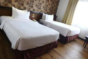 2 Betten in einem Hotelzimmer neben einem Fenster in der Unterkunft Jakarta Airport Hotel in Tangerang