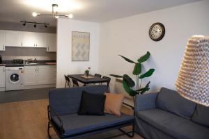 a living room with two blue couches and a kitchen at Modern 2 bed Apartment- Town Centre in Northampton