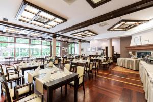 a restaurant with tables and chairs in a room with windows at Dom Crocus in Zakopane