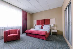 エッセントゥキにあるБизнес-отель "Эринии"のベッドと赤い椅子が備わるホテルルームです。