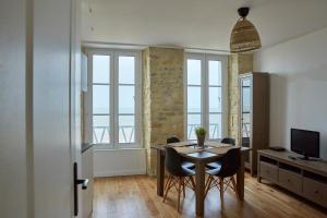 une salle à manger avec une table, des chaises et des fenêtres dans l'établissement Appartement front mer proche omaha & utah beach - 2, à Grandcamp-Maisy