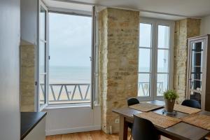 a dining room with a table and a view of the ocean at Appartement front mer proche omaha & utah beach - 2 in Grandcamp-Maisy