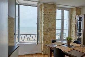 une salle à manger avec une table et une vue sur l'océan dans l'établissement Appartement front mer proche omaha & utah beach - 2, à Grandcamp-Maisy