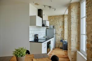 una cocina con electrodomésticos blancos y una mesa en una habitación en Appartement front mer proche omaha & utah beach - 2, en Grandcamp-Maisy
