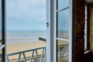 una vista de una playa desde una ventana en Appartement front mer proche omaha & utah beach - 2, en Grandcamp-Maisy