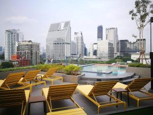 un grupo de sillas y una piscina en un edificio en The Quart Ruamrudee by UHG - Extra Plus, en Bangkok