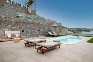 a patio with a pool and chairs and a building at Ligaria Mare in Agia Pelagia