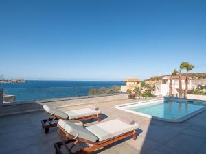 a patio with chairs and a swimming pool and the ocean at Ligaria Mare in Agia Pelagia