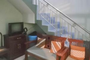 ein Wohnzimmer mit einer Bank und einer Treppe in der Unterkunft TRIYOGA Homestay Syariah RedPartner in Sangkanurip