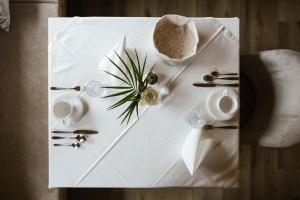 a white table with silverware and a plant on it at Garni Hotel Platzer in Burgusio