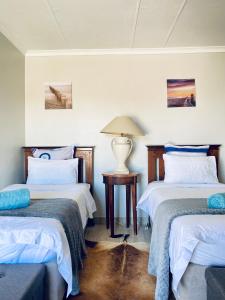 a room with two beds and a lamp on a table at Country Lane Farm lodge in Cradock