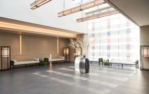 un hall avec des bancs et un vase planté d'arbres dans l'établissement Nine Tree Premier Hotel Insadong Myeongdong, à Séoul