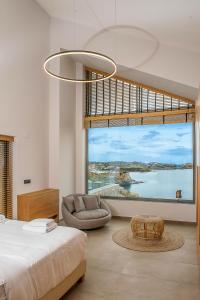 a bedroom with a large window with a bed and a chair at Ligaria Mare in Agia Pelagia