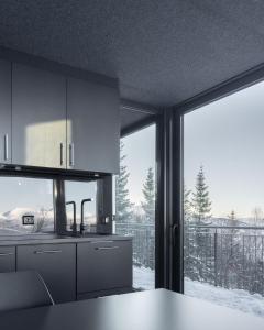 uma cozinha com uma grande janela com neve no chão em NARVIKFJELLET Camp 291 em Narvik