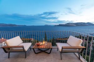 a balcony with two chairs and a table and the ocean at Born in Blue in Kaş