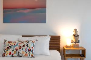 a bed with a pillow and a table with a lamp at Born in Blue in Kaş