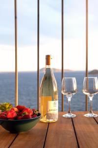 a bottle of wine and a bowl of fruit on a wooden table at Born in Blue in Kaş