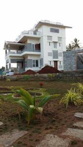 un gran edificio blanco frente a un patio en DWARAKA STAY INN-Rejoicing Family Home Coorg, en Kushālnagar