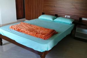 Una cama con una manta naranja encima. en DWARAKA STAY INN-Rejoicing Family Home Coorg, en Kushālnagar