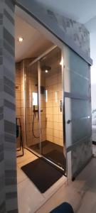 een badkamer met een douche en een glazen deur bij Chez Seb & Lulu, studio d'hôtes in Neufchâteau