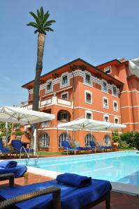 a hotel with a swimming pool with chairs and a palm tree at Hotel 1908 in Forte dei Marmi