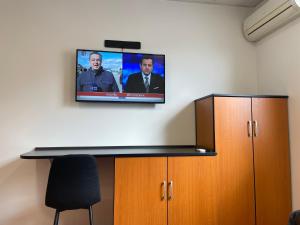 una TV a schermo piatto appesa a un muro sopra una scrivania di Room AA a Dravograd