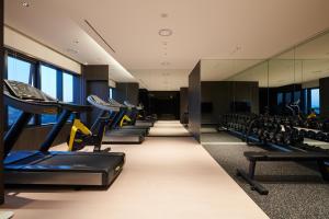 a gym with a row of treadmills and chairs at Nine Tree Premier Hotel Seoul Pangyo in Seongnam