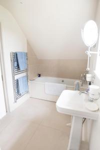 biała łazienka z umywalką i wanną w obiekcie The Countryside Annexe w mieście Pulborough