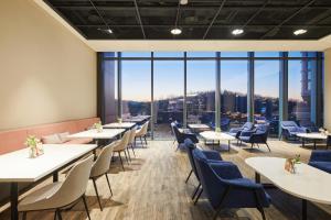 a restaurant with tables and chairs and large windows at Nine Tree by Parnas Seoul Pangyo in Seongnam