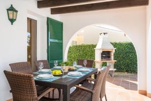 una sala da pranzo con tavolo, sedie e camino di Villa Androna a Cala'n Bosch