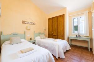 a room with two beds with white sheets at Villa Androna in Cala'n Bosch