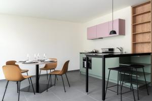 una cucina con tavolo, sedie e armadietti rosa di Townhouse N9 a Sankt Moritz
