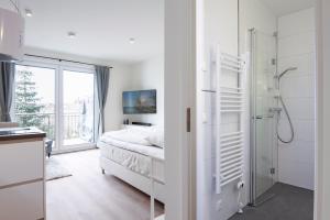 a white bedroom with a bed and a shower at Pier 67 Kleine Perle Neustadt in Neustadt in Holstein