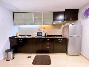 a kitchen with brown cabinets and a stainless steel refrigerator at Sunway Resort Suite @ Sunway Pyramid Lagoon View in Petaling Jaya