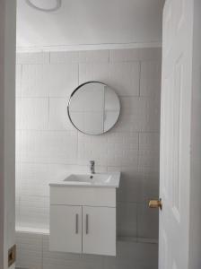 ein weißes Badezimmer mit einem Waschbecken und einem Spiegel in der Unterkunft Hostal Doñihue in Doñihue
