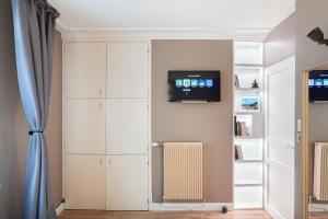 シャンティイにあるSuite Appart Place Versepuyの白いキャビネットと壁掛けテレビが備わる客室です。