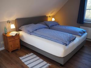 - un lit avec des oreillers bleus et blancs et une table de nuit dans l'établissement Ferienhof Hage, à Hüde