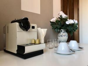 uma cafeteira e um vaso com flores sobre uma mesa em Zen Garden em Bassano del Grappa