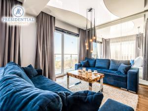 a living room with blue couches and a table at Prezydencki Apartamenty in Jarosławiec