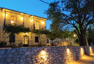 a white house with lights on a stone wall at Fox Tale Guest House in Fternón