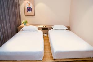 duas camas num pequeno quarto com lençóis brancos em 银座佳驿（潍坊寒亭高铁北站店） em Weifang
