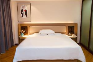 um quarto com uma grande cama branca num quarto em 银座佳驿（潍坊寒亭高铁北站店） em Weifang