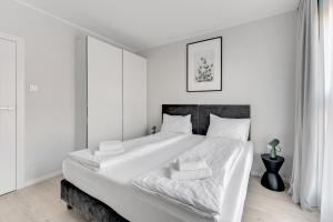 a white bedroom with a large bed with white sheets at Comfort Apartments Grano Residence in Gdańsk