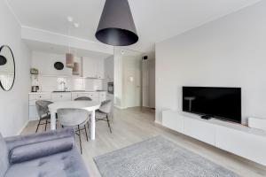 a white living room with a table and a tv at Comfort Apartments Grano Residence in Gdańsk