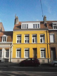 une maison jaune avec une voiture garée devant elle dans l'établissement Bruneval House, à Dunkerque