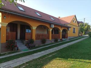 una casa amarilla con techo rojo en Nádkunyhó Vendégház, en Hegyhátszentjakab